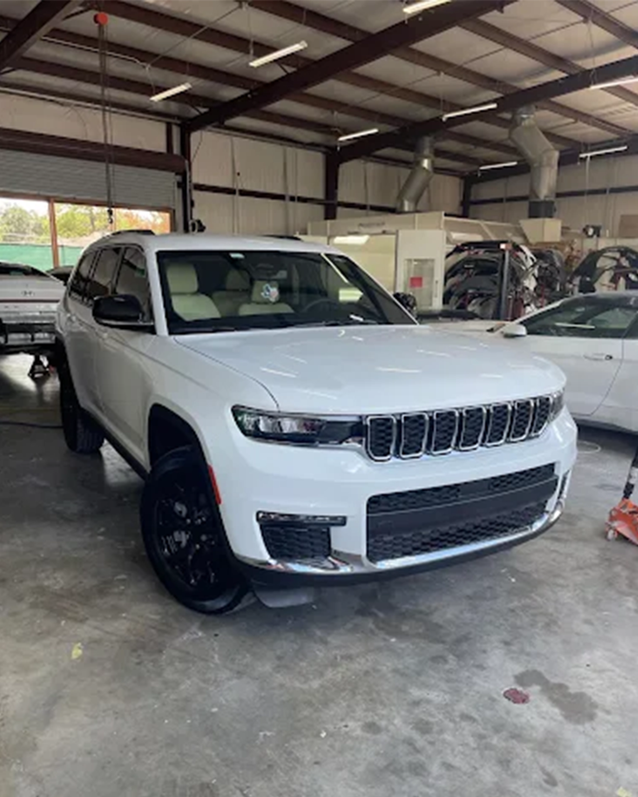 Freshly repaired white SUV parked inside an auto body shop, showcasing a clean front end and detailed finish after collision or paint work.